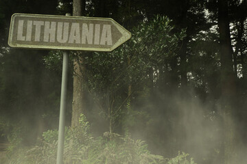 old signboard with text lithuania near the green sinister forest
