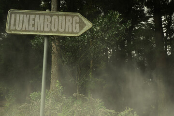 old signboard with text luxembourg near the green sinister forest