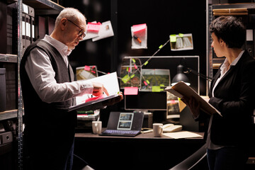 Federal agents working overhours at criminal case, analyzing criminology report in arhive room....
