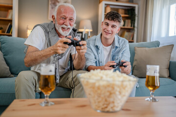 teenager male and his grandfather senior man play console video game