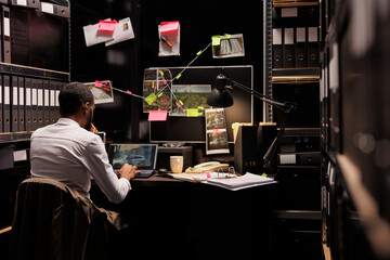Private detective checking surveillance photos on laptop, spying on suspect for client. African...