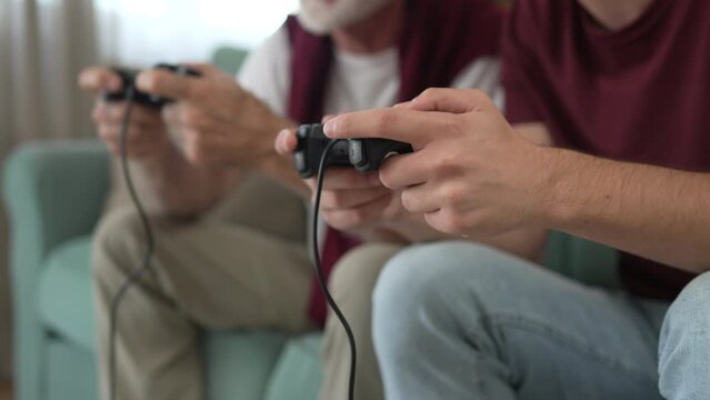 teenager male and his grandfather senior man play console video game
