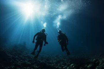 Fotobehang two scuba divers diving deep next to a bank of fishes © urdialex