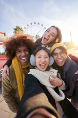 Vertical excited smiling group multiracial friends taking funny selfie looking at camera standing...