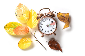 Fall back in autumn after daylight saving time in summer on a vintage alarm clock and some colored...
