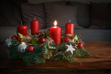 Advent wreath with one burning red candle and Christmas decoration on a wooden table in front of...