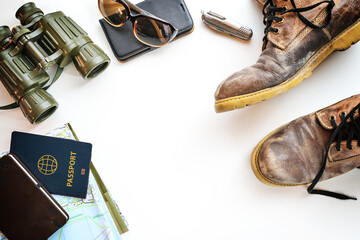 Trekking boots, binoculars, passport and other accessories for hiking vacation, flat lay on a light background, copy space