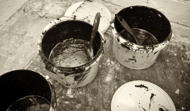 Workers at a repair company mix two-component black epoxy resin for a bridge restoration project.