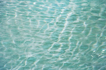 Defocus blurred transparent blue colored clear calm water surface texture with splashes reflection. Trendy abstract nature background. Water waves in sunlight with copy space. Blue watercolor shine