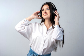 latin young woman with headphones very happy gesturing cheerful wearing white shirt and white...