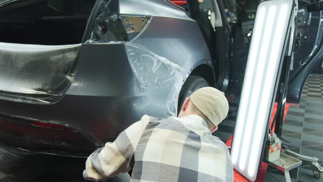 Process of applying a protective PPF film to a car. worker applying a protective film on a car. 