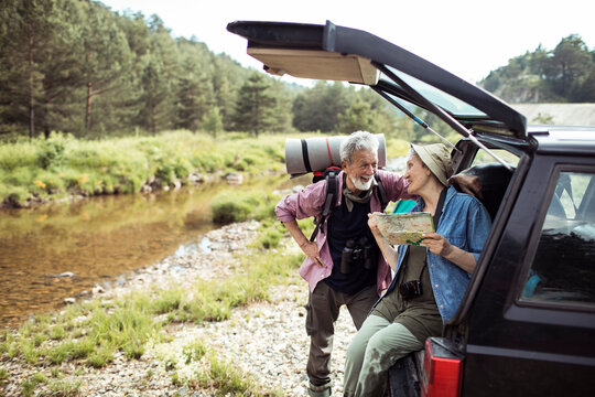 Two senior friends looking at the map while out hiking and camping in the forest