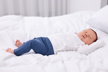 Cute newborn baby sleeping on white bed at home