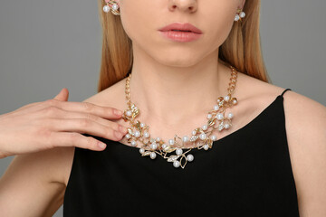 Woman with elegant jewelry on gray background, closeup