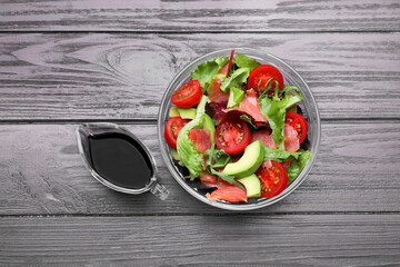 Tasty soy sauce and bowl with salad on wooden table, flat lay