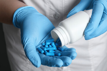 Obraz premium Doctor pouring pills from bottle onto hand, closeup view