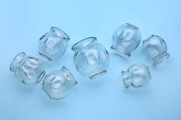 Many glass cups on light blue background, flat lay. Cupping therapy