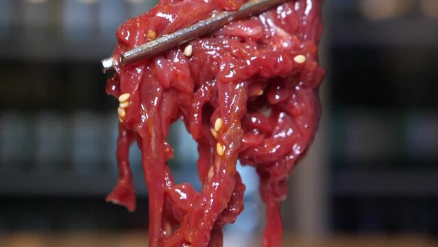 신선한 육회 위에 얹은 계란 노른자를 젓가락으로 터트려 비빈 육회 한 젓가락 클로즈업