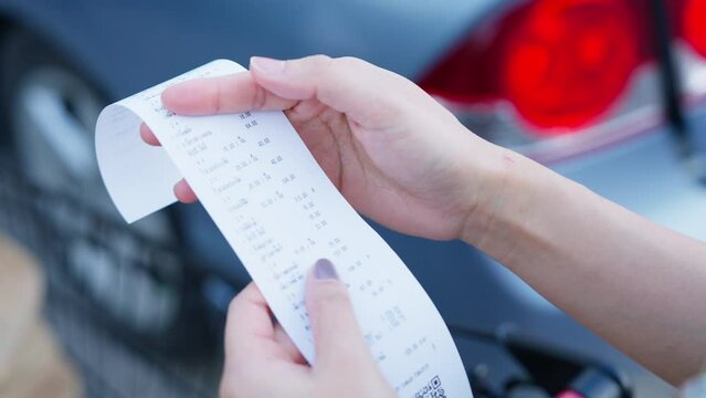 Close-up shot of female shopper checking receipt She calculates the money and checks its accuracy