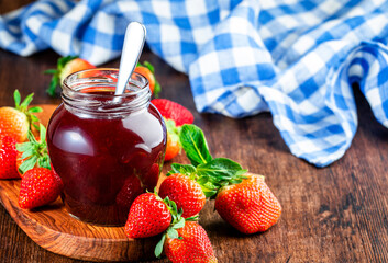 Homemade strawberry jam or confiture in glass jar and fresh berries, rustic wooden table...