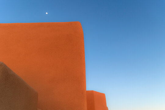 USA, New Mexico, Santa Fe, Moon in blue sky above adobe walls