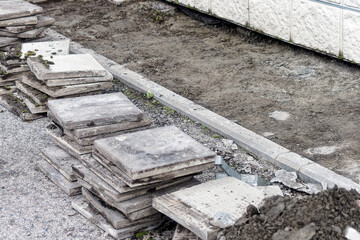 Facing concrete tiles lie on ground in stack. Replacing building foundation. Repair and construction. Background.