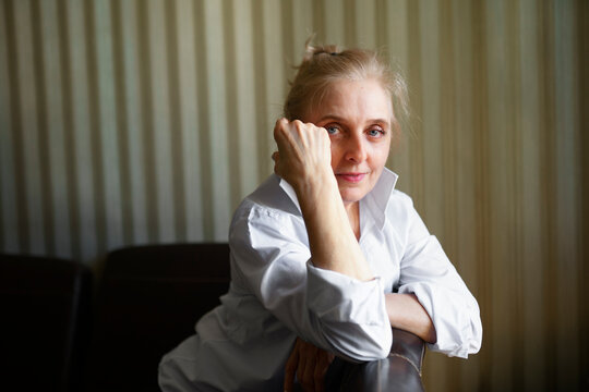 Portrait of woman leaning on sofa backrest and looking at camera&nbsp;