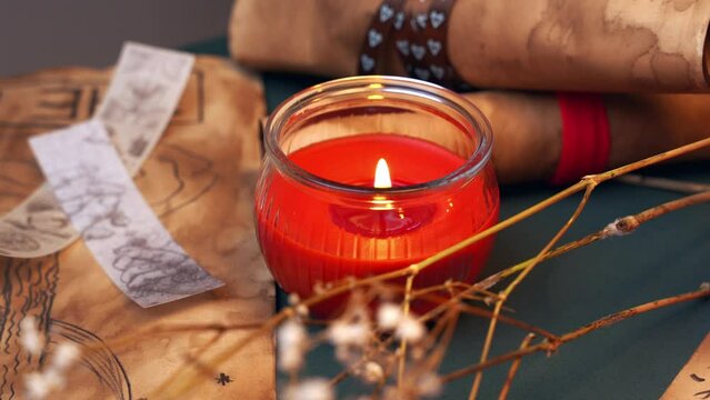 Close-up of interior decor, esoteric aroma spa red burning candle, dry branch, parchment scroll, fortune cookie. Predictions, fortune teller table, chakra opening, relaxation. Candle flame in memory