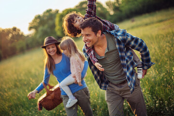 Young Caucasian family having fun and walking on a field in a park