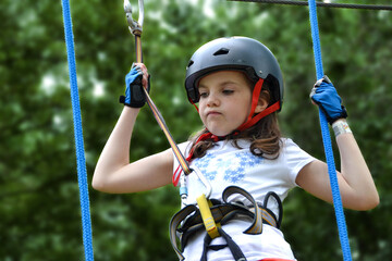 adventure climbing high wire park - people on course in mountain helmet and safety equipment. - Powered by Adobe
