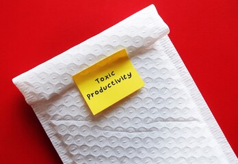 Stick note on bubble envelope written TOXIC PRODUCTIVITY, means desire for productivity at all...
