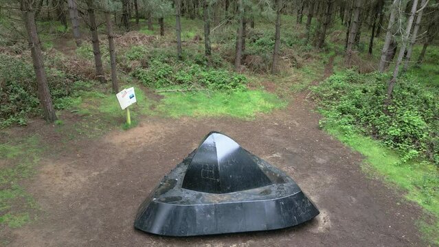 Aerial view rising above Rendlesham forest realistic flying saucer exhibit on the woodland park UFO trail