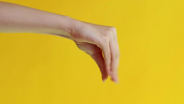 Vertical video. Cleaning game. Hygiene tools. Hand in safety protective gloves washing woman arm with pink sponge isolated on yellow background.