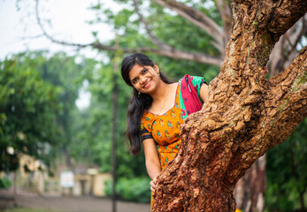 Young girl near tree trunk and she enjoying fresh air outdoors