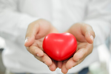 Man holding red heart shaped rubber.