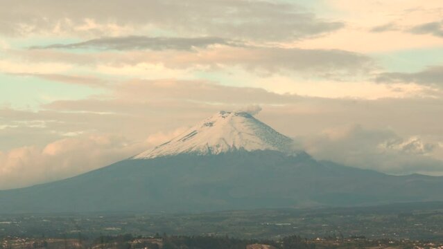 Scenic View of Cotopaxi Volcano with a Plume of Smoke Drifting from its Peak in Ecuador from a Faraway Shot of the Mountain with Cloudy Skies Overhead.