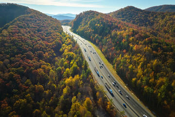 Aerial view of I-40 freeway in North Carolina heading to Asheville through Appalachian mountains in golden fall with moving trucks and cars. Interstate transportation concept