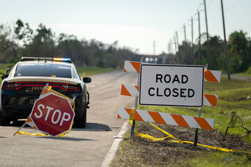Police patrol car at yellow protective barrier at street construction site. Warning road sign about...