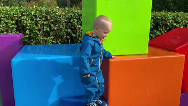 toddler child in amusement park, happy little boy climbing on colorful cubes. Divo Ostrov, St. Petersburg, Russia