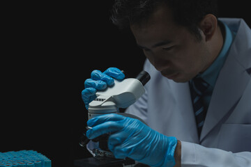 Asian scientist looking at a microscopic sample of experimental cyan is doing an in vitro vaccine...