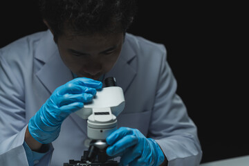 Asian scientist looking at a microscopic sample of experimental cyan is doing an in vitro vaccine...