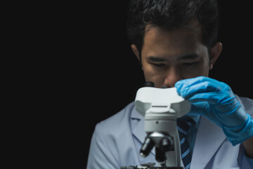 Asian scientist looking at a microscopic sample of experimental cyan is doing an in vitro vaccine...