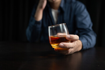 Asian businessman stressed at work failed business problem paperwork Desperate man holding a glass of alcohol Sitting at the desk late at night in the office Depressed and hopeless concept.