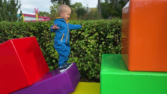 toddler child in amusement park, happy little boy climbing on colorful cubes. Divo Ostrov, St. Petersburg, Russia