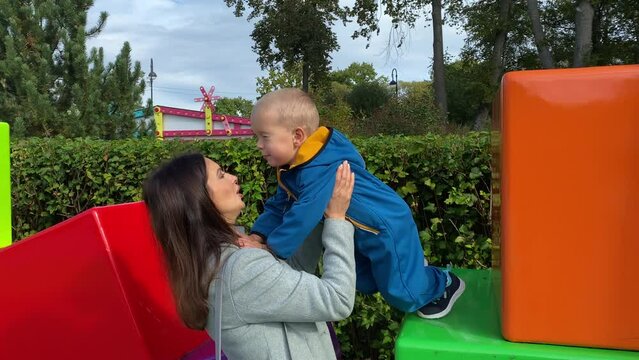 mother with toddler child in amusement park, happy little boy climbing on colorful cubes. Divo Island, St. Petersburg, Russia