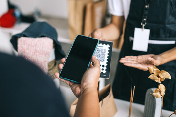 Customer using phone for payment at the market. Cashless QR code technology and money transfer concept.