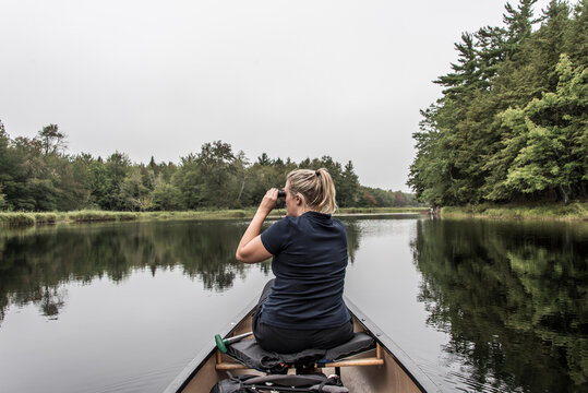 blonde Girl Canoe ride exploring nature on morning mist Kejimkujik National Park Wilderness Nova Scotia Canada
