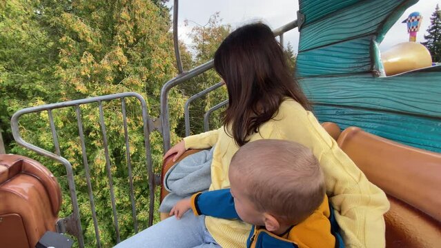 mother with child enjoy views of amusement park from height of 4 meters, traveling in a mobile, Divo Ostrov, St. Petersburg, Russia