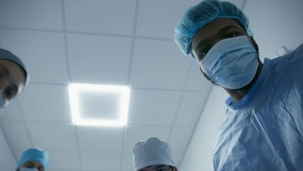Multiethnic doctors check condition of patient before operation. African American surgeon talks to patient and puts breathing tube. Medics transport patient to operation room. Medical staff at work.