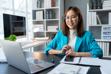 Asian business woman working using laptop computer, marketing report with calculator document on...